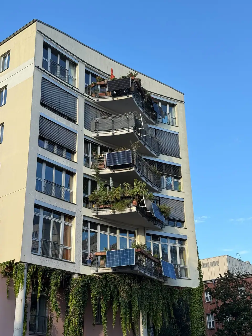 Solar panels mounted on the balcony railings of a multi-story apartment building in Berlin under a blue sky