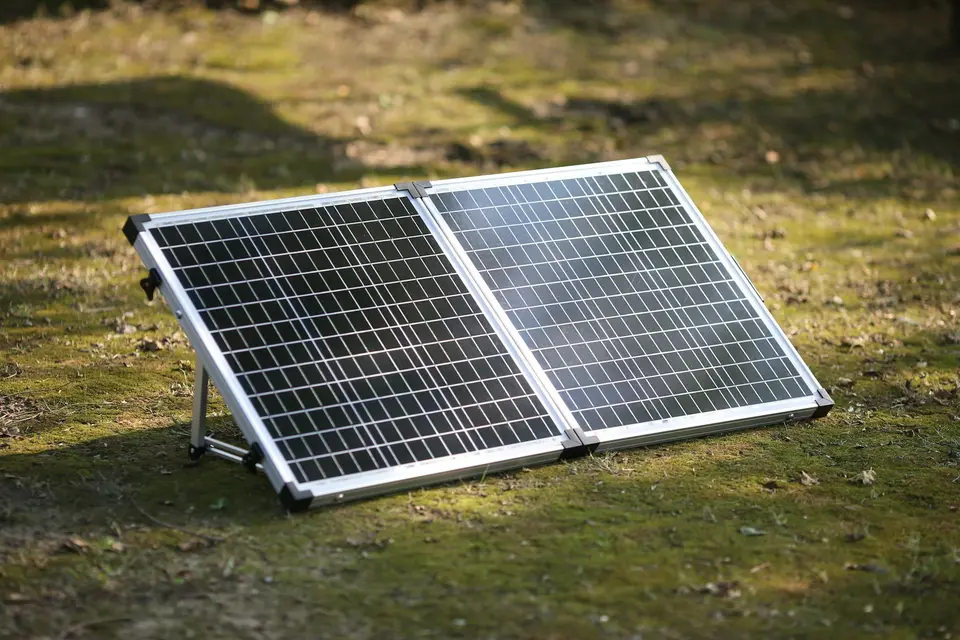 A foldable two-panel portable solar panel standing on its kickstand in the grass
